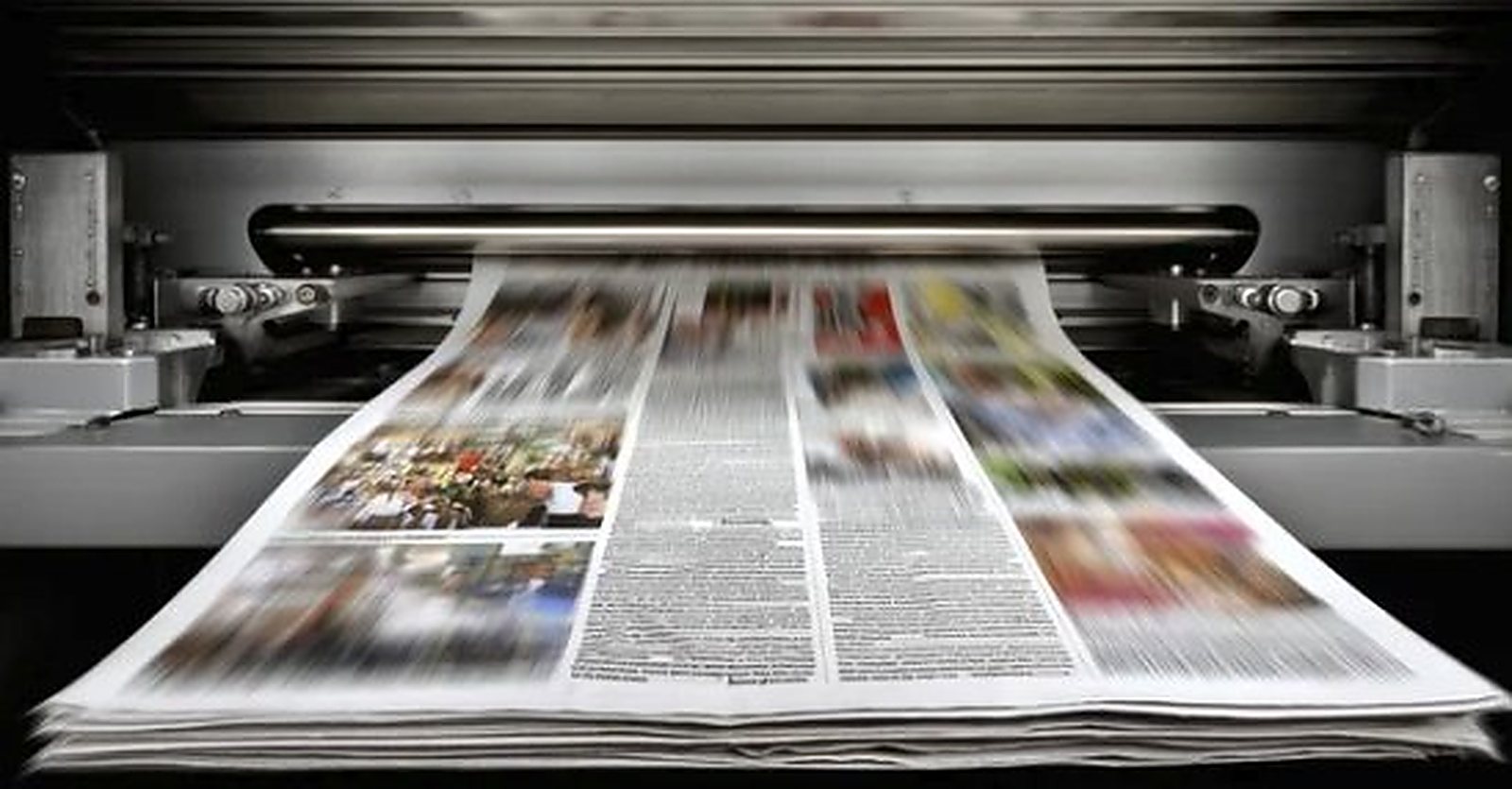 Newspaper pages running through a printing press at speed.