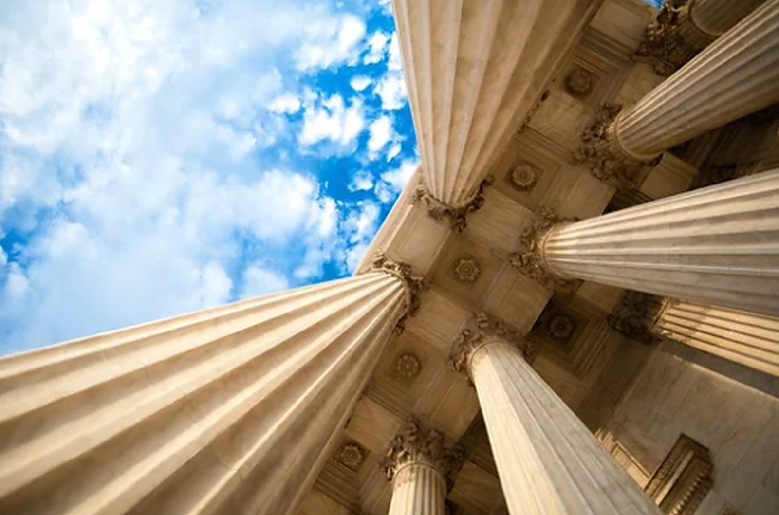 Classical stone columns of a courthouse seen from below.