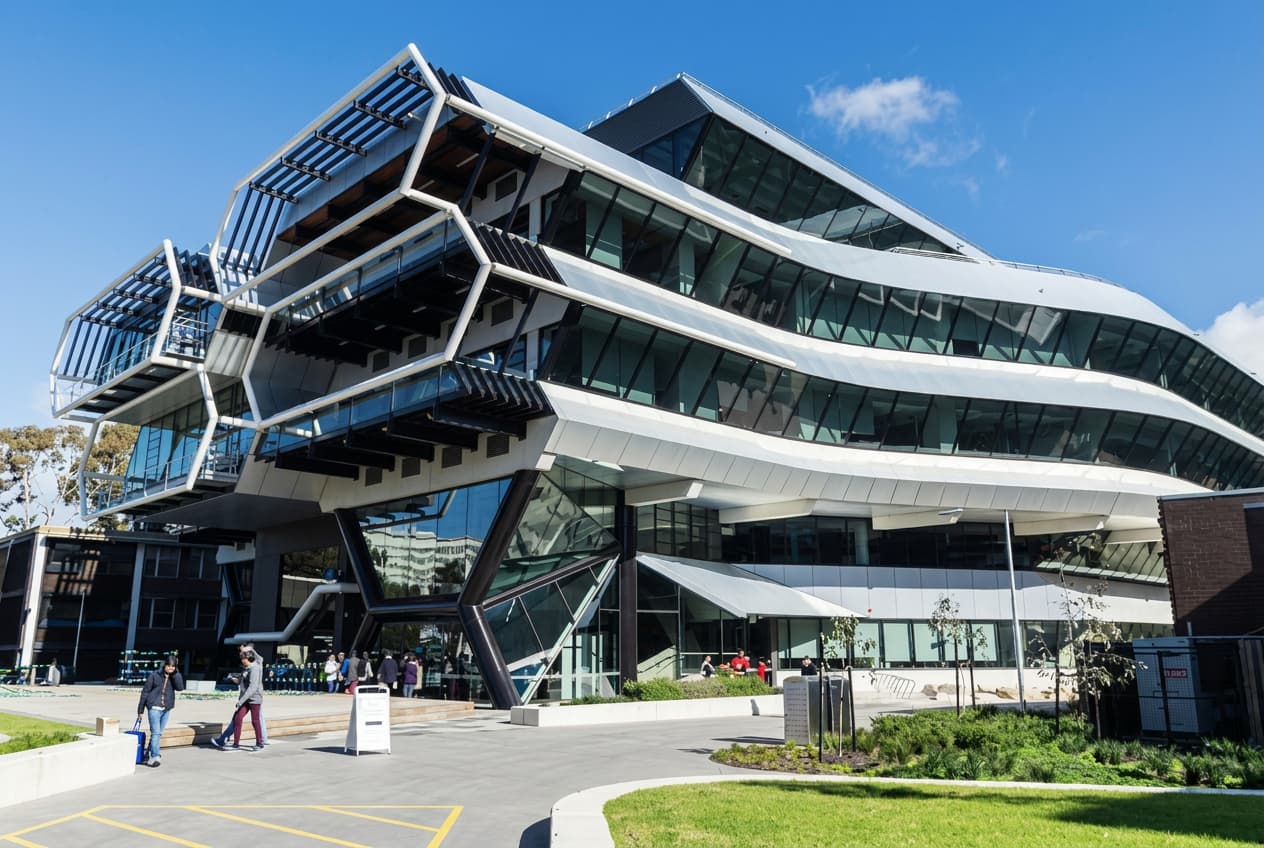 A contemporary university building with stacked glass floors against a deep blue sky.