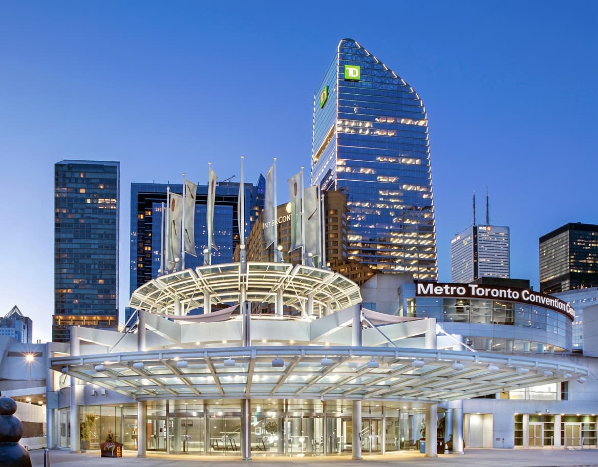 Downtown Toronto at dusk with lit towers behind an illuminated entrance canopy.
