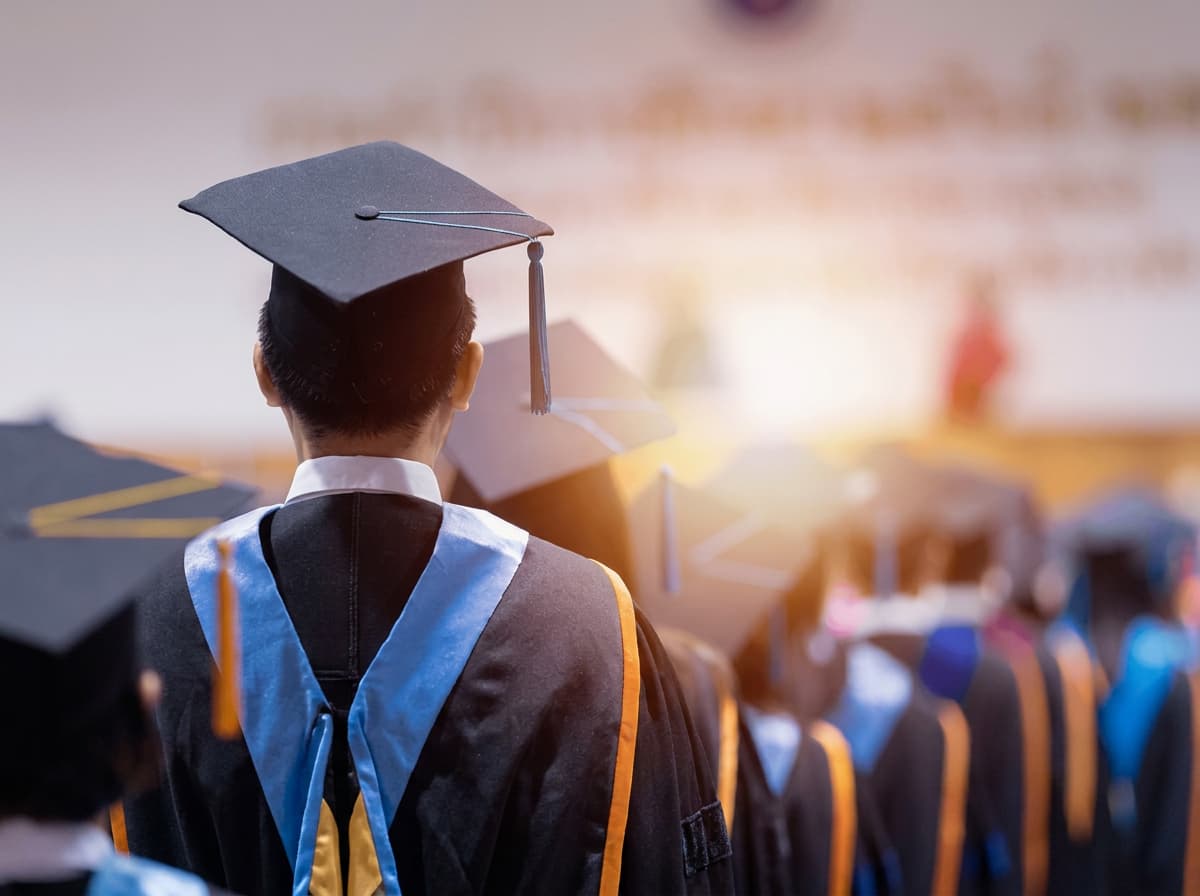 Graduates in gowns and gold hoods walking in a graduation procession.