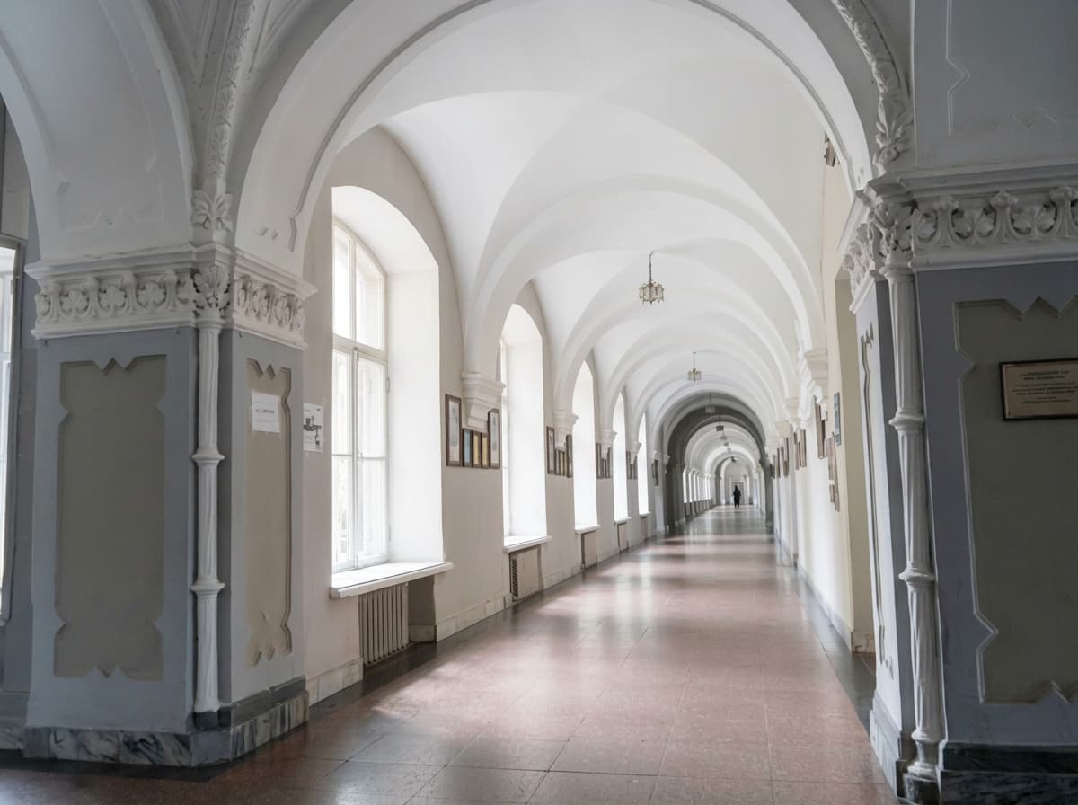 A long white vaulted corridor in a historic university building.