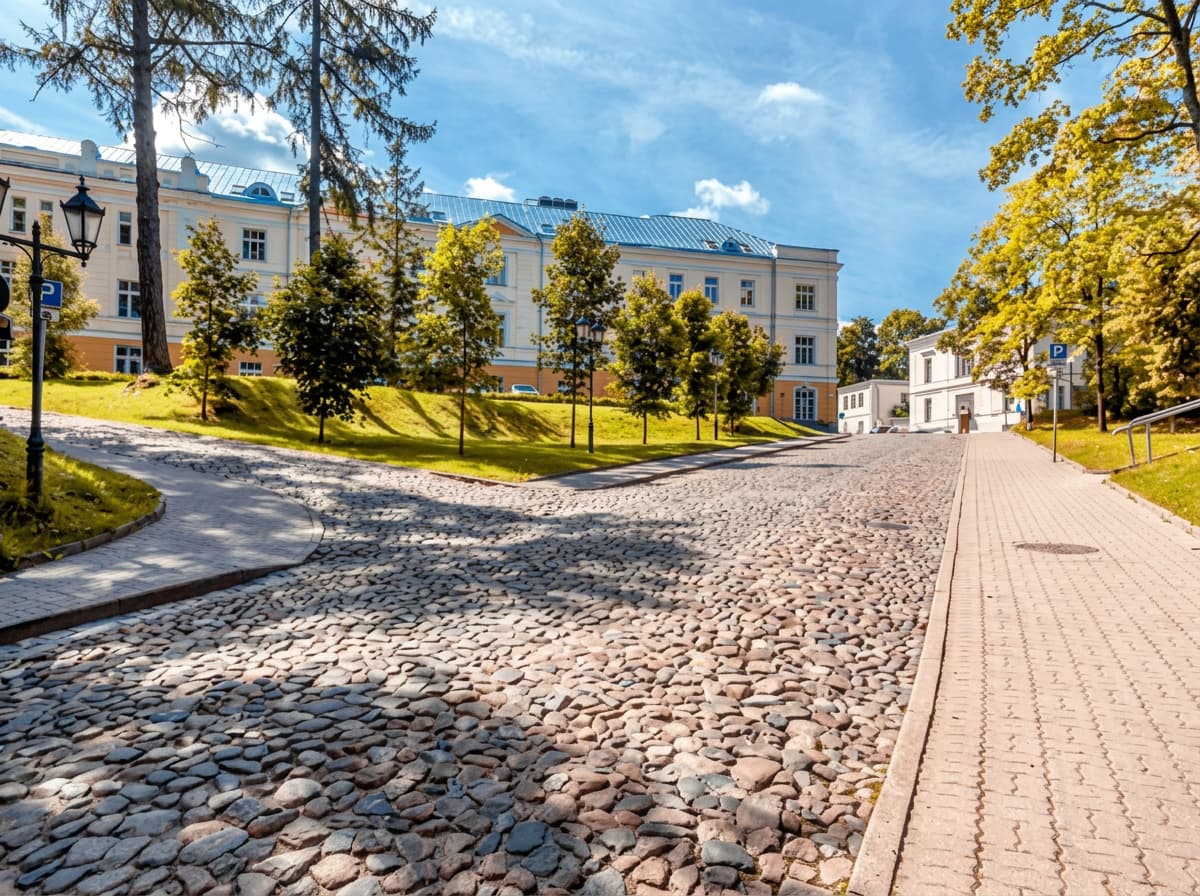 A cobblestone square in front of a cream-coloured European university building.