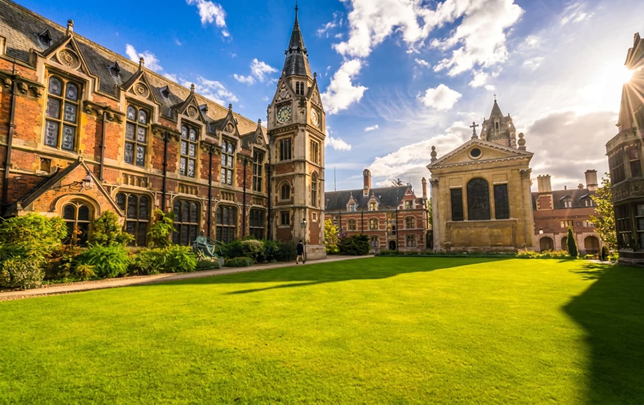 A historic UK university quadrangle with a clock tower and open lawn.