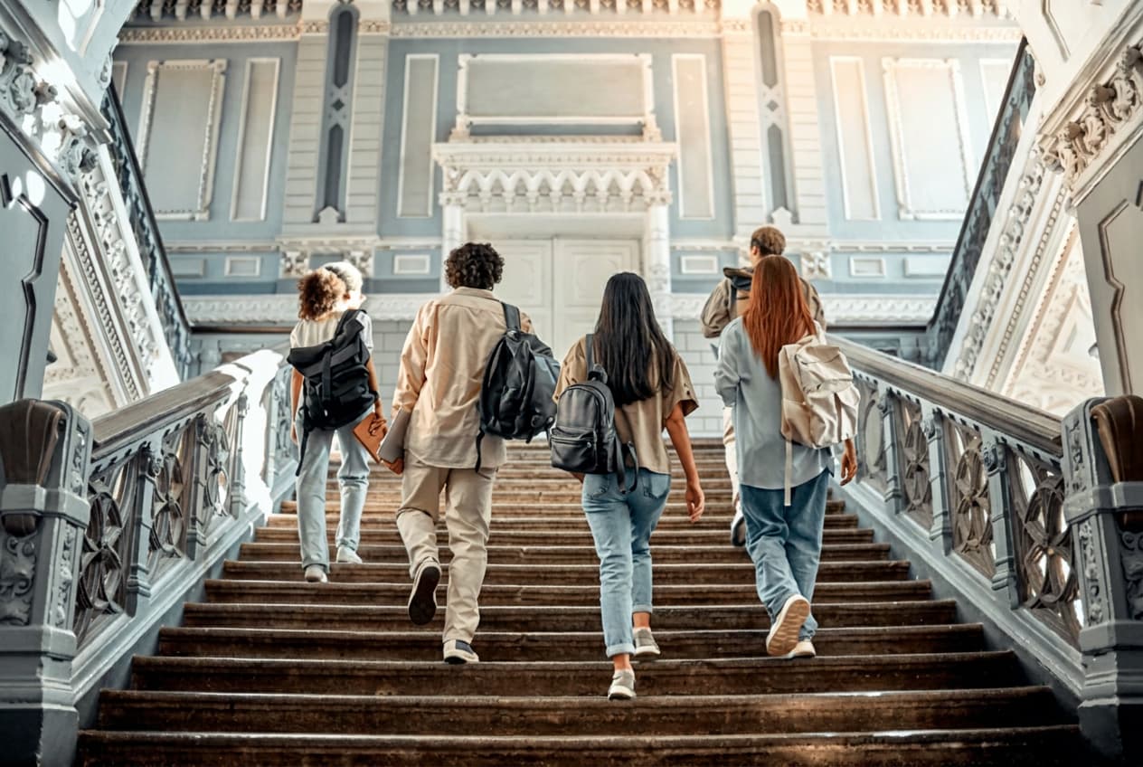 Students climbing a grand university staircase.
