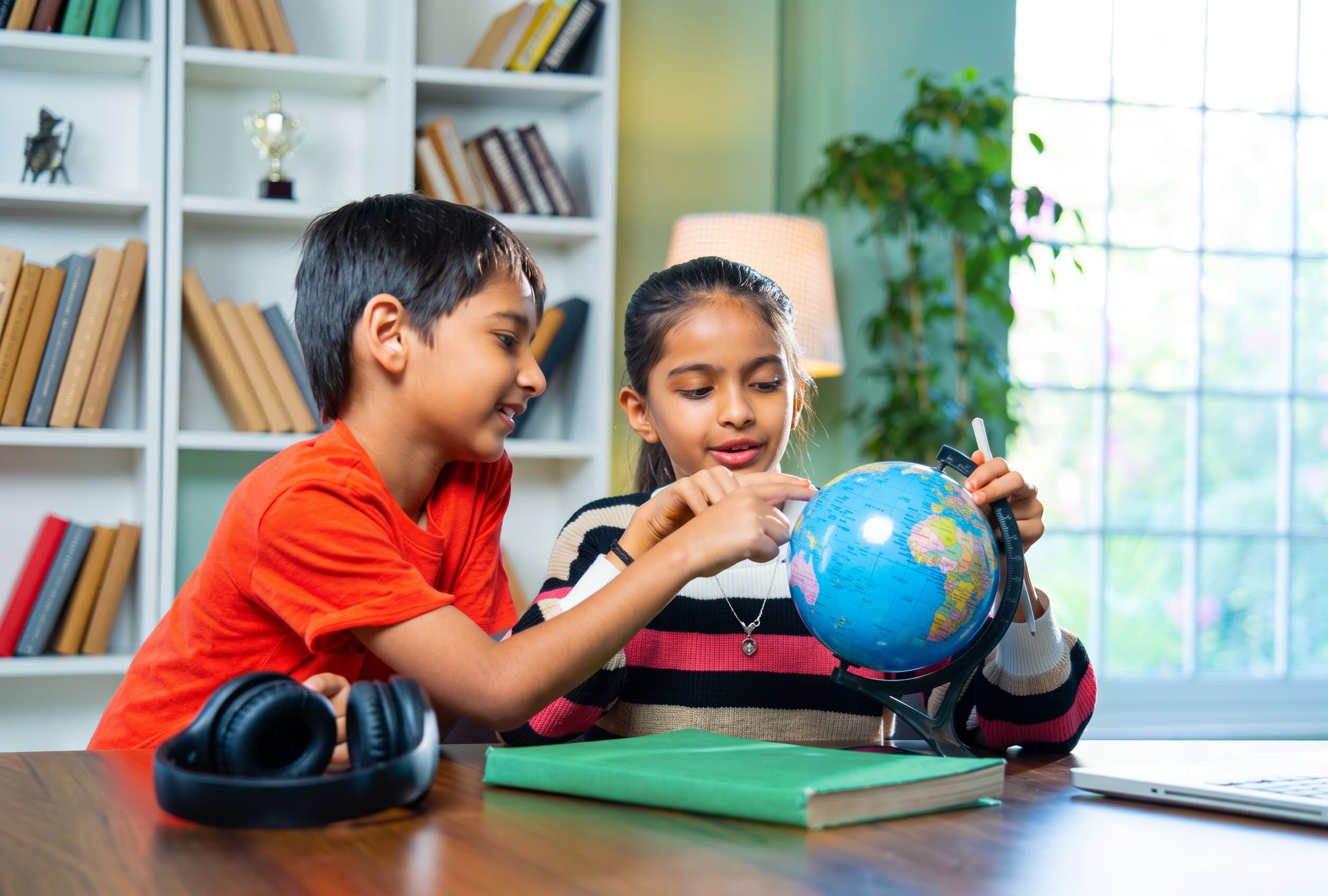 Two younger students examining a globe as they prepare to study abroad.