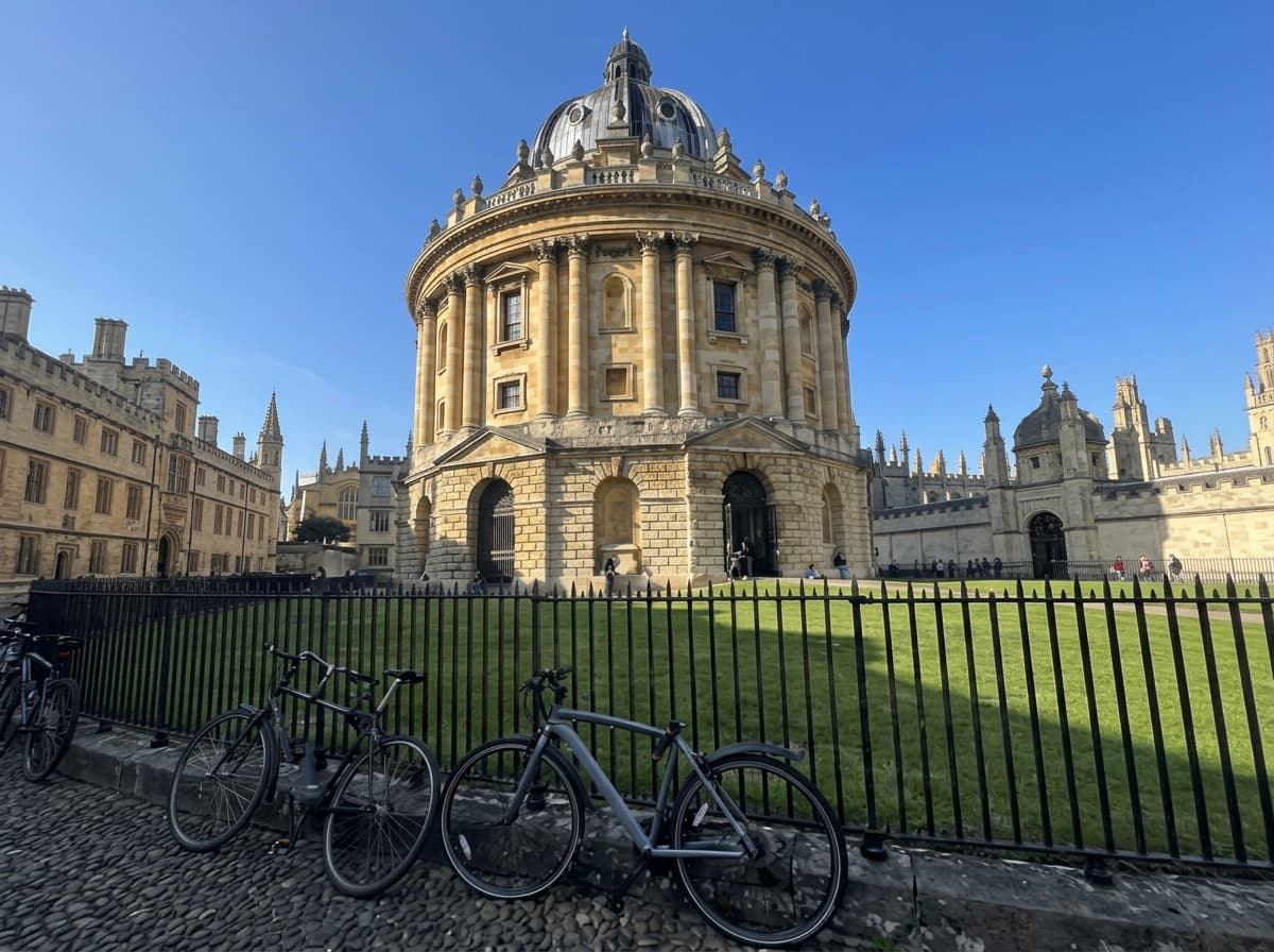 A domed honey-stone university library under a bright blue sky, with bicycles parked along the railings.